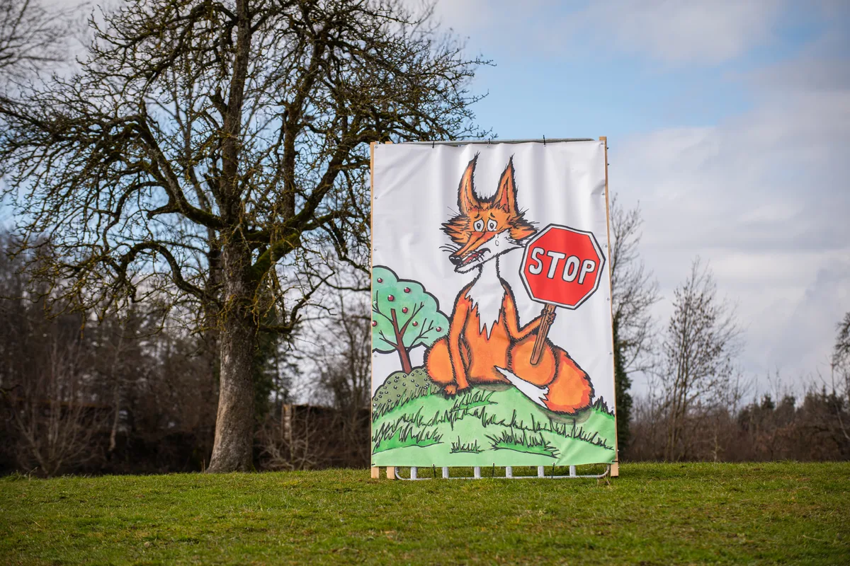 Ein Protest-Plakat mit einem weinenden Fuchs auf einer grossen Wiese.
